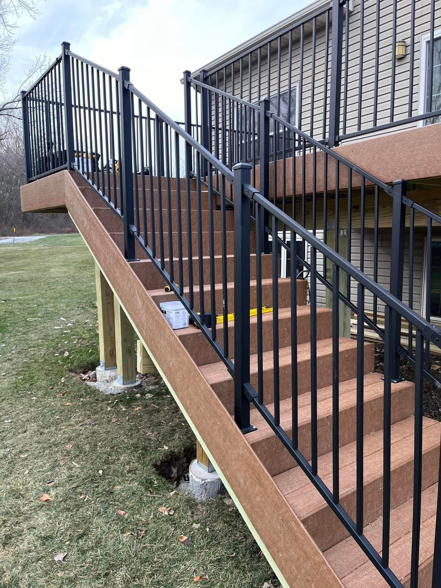 A set of stairs leading up to a deck with a metal railing.