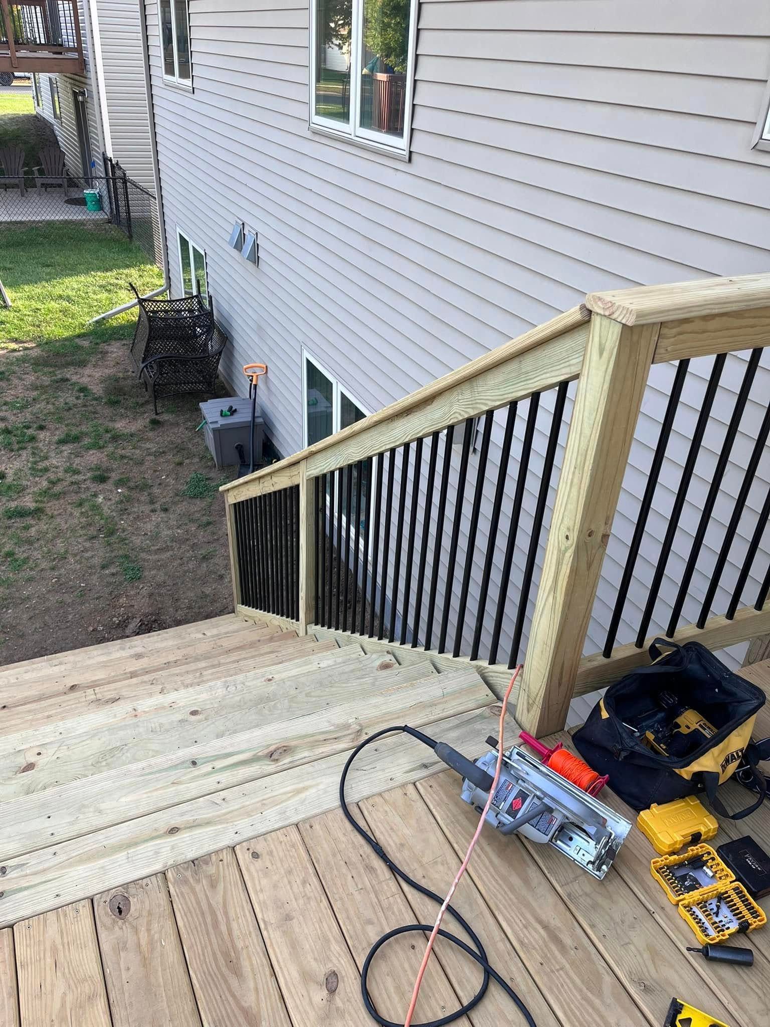 A wooden deck with stairs being built next to a house.