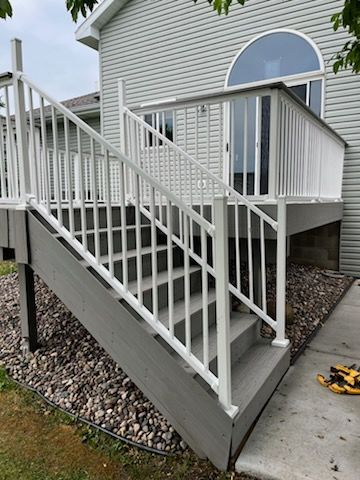A deck with stairs leading up to it and a white railing.