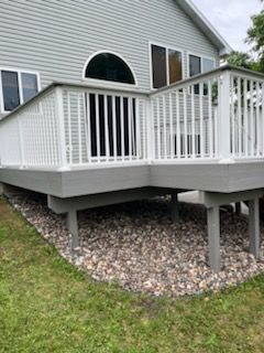 A white deck with a white railing is in front of a house.