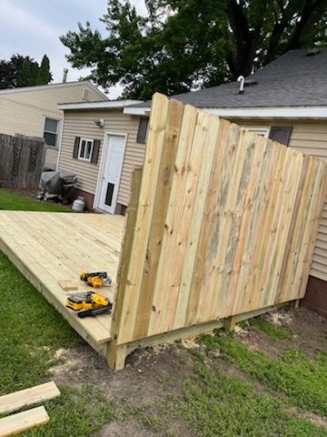 A wooden deck is being built next to a wooden fence.