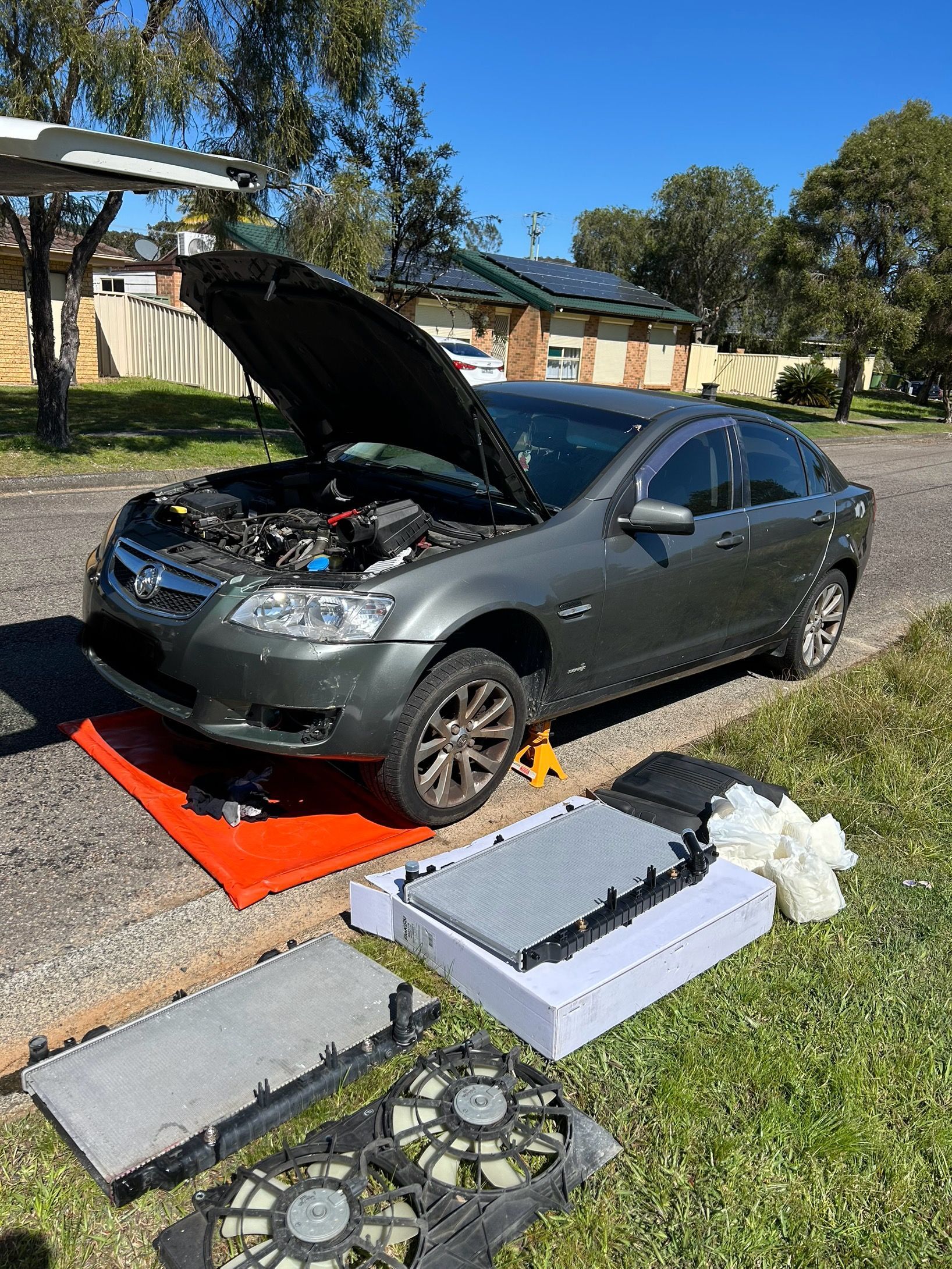 Gray sedan with hood open, tools and parts laid out on grass for repair. — All Auto & Mechanical in  Erina, NSW