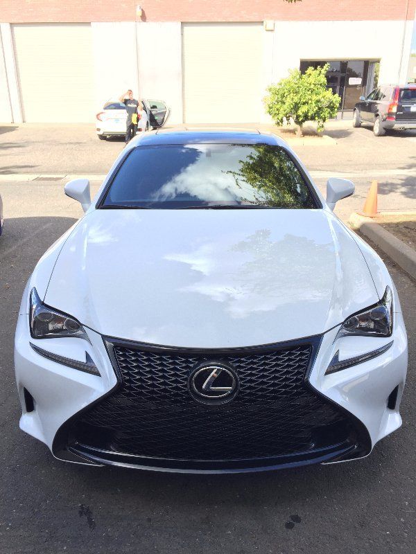 A white lexus is parked in a parking lot.
