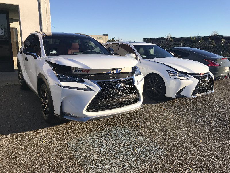 Two white lexus cars are parked next to each other in a parking lot.