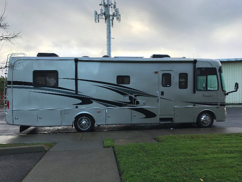 A large white rv is parked on the side of the road.