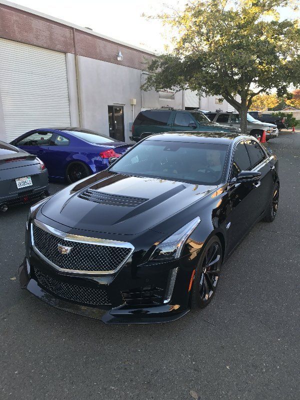 A black cadillac cts is parked in front of a building.