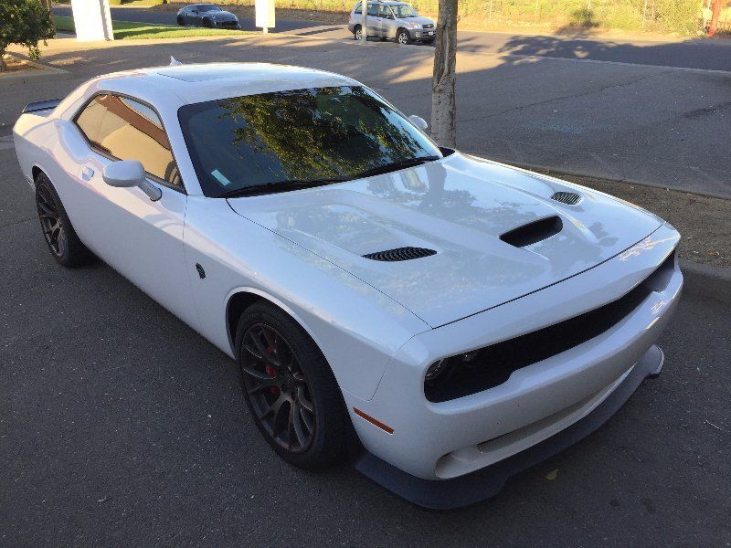 A white dodge challenger is parked on the side of the road
