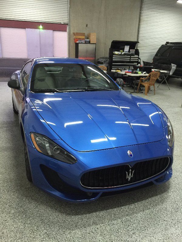 A blue maserati is parked in a garage.