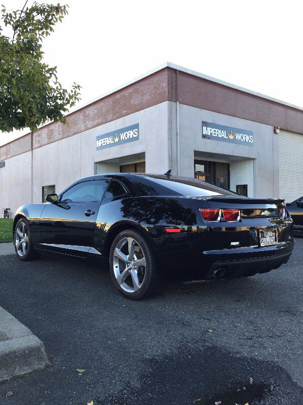 A black car is parked in front of a building that says imperial works