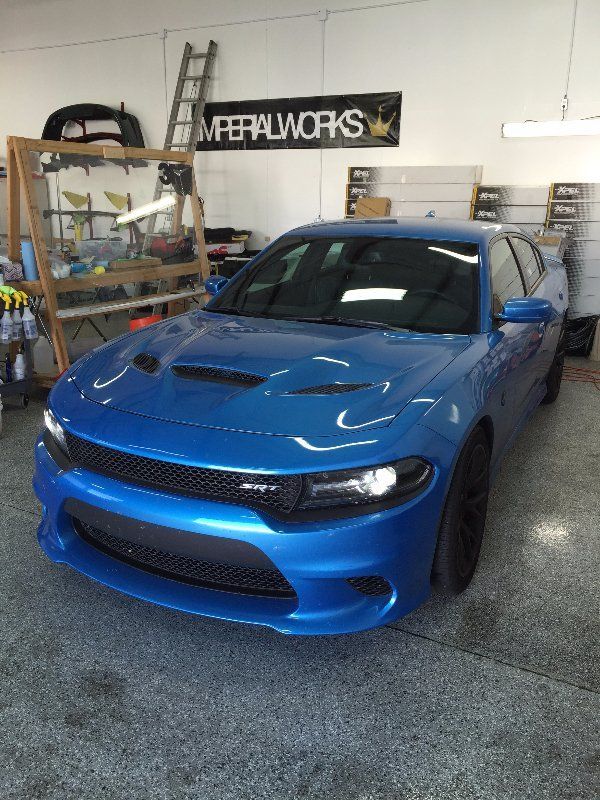 A blue dodge charger is parked in a garage