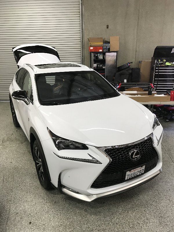 A white lexus nx is parked in a garage with the trunk open.