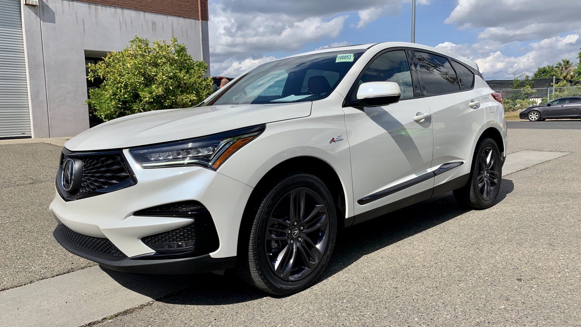 A white acura integra is parked on the side of the road in front of a building.