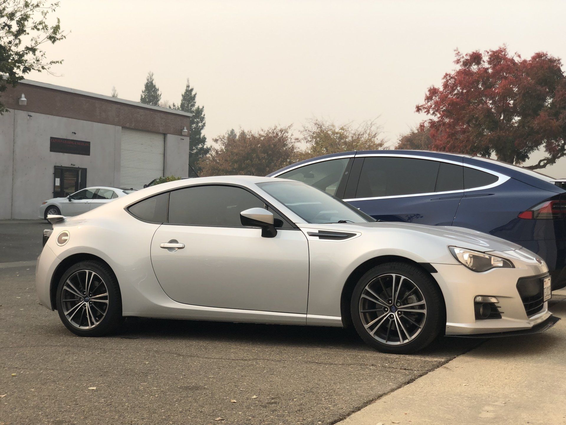 A silver sports car is parked next to a blue car.
