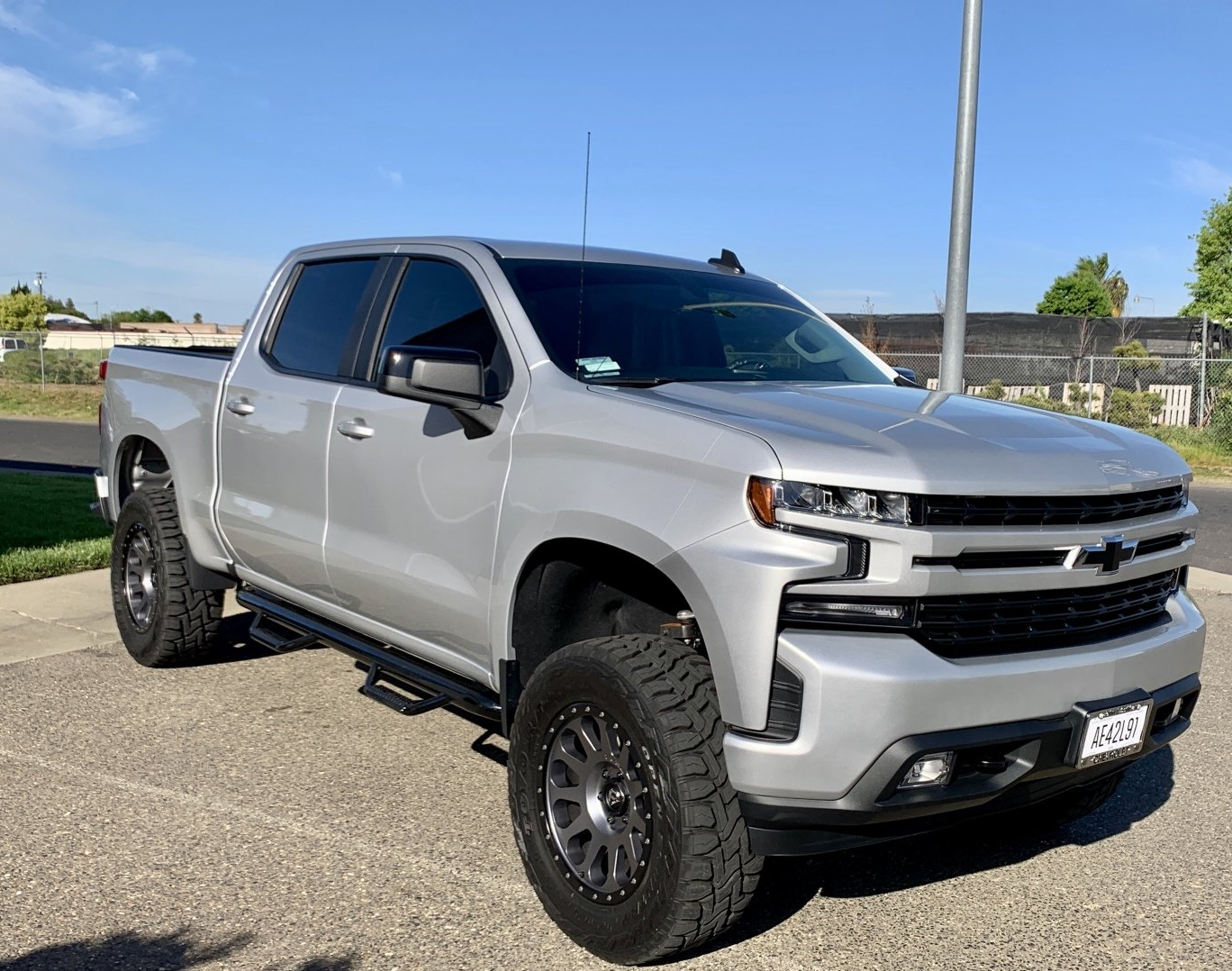 A silver pickup truck is parked on the side of the road.
