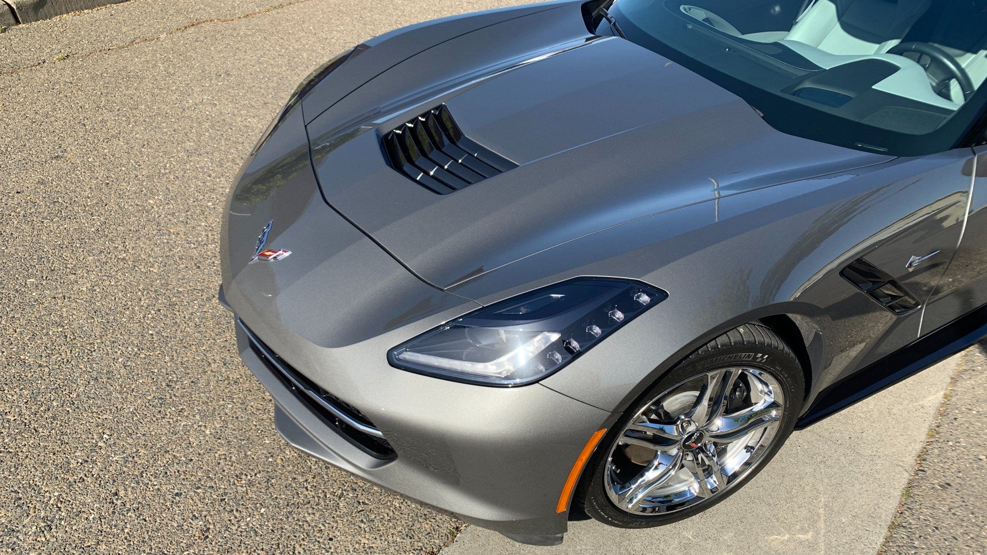 A gray corvette is parked on the side of the road.