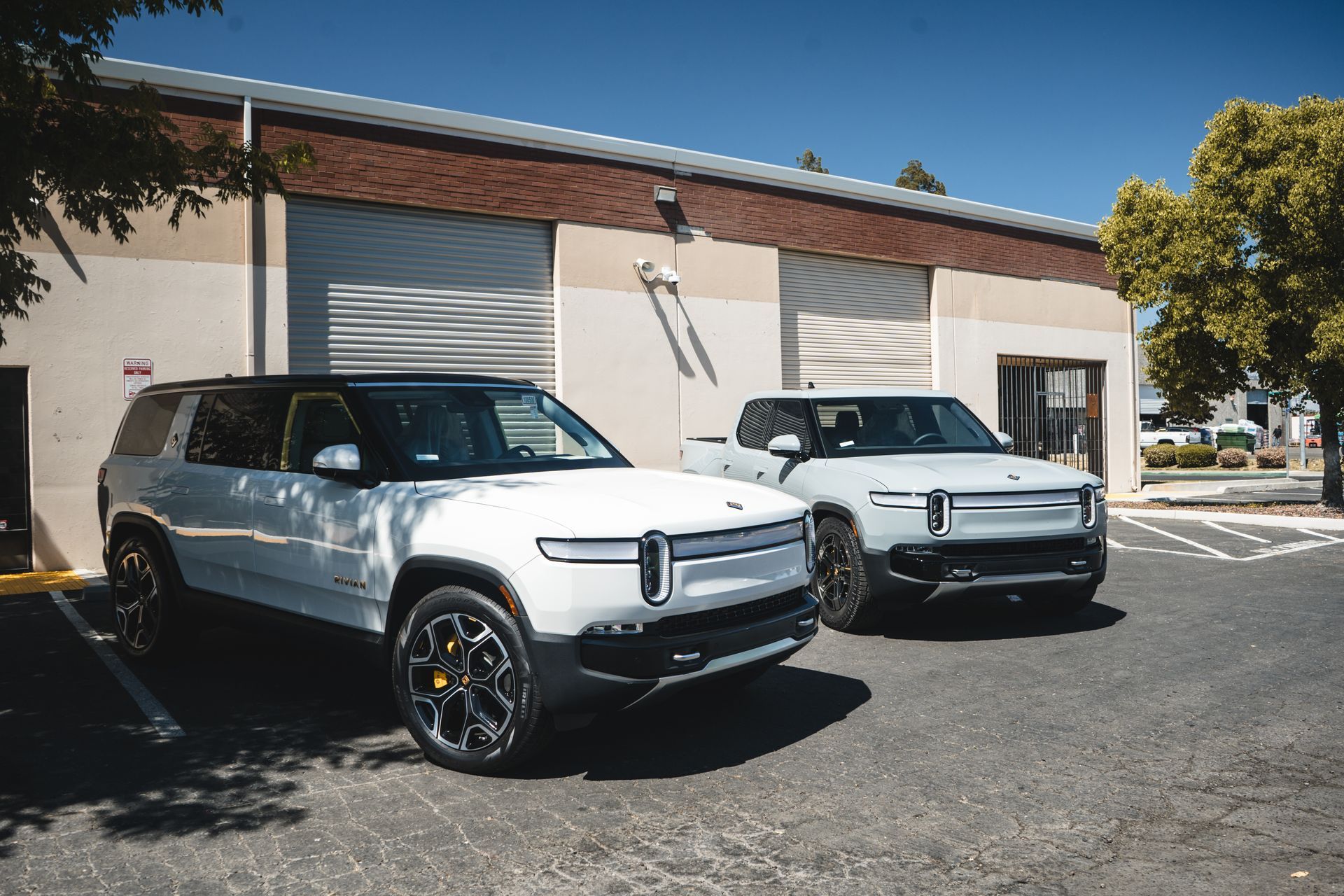 Two white cars are parked in front of a building.