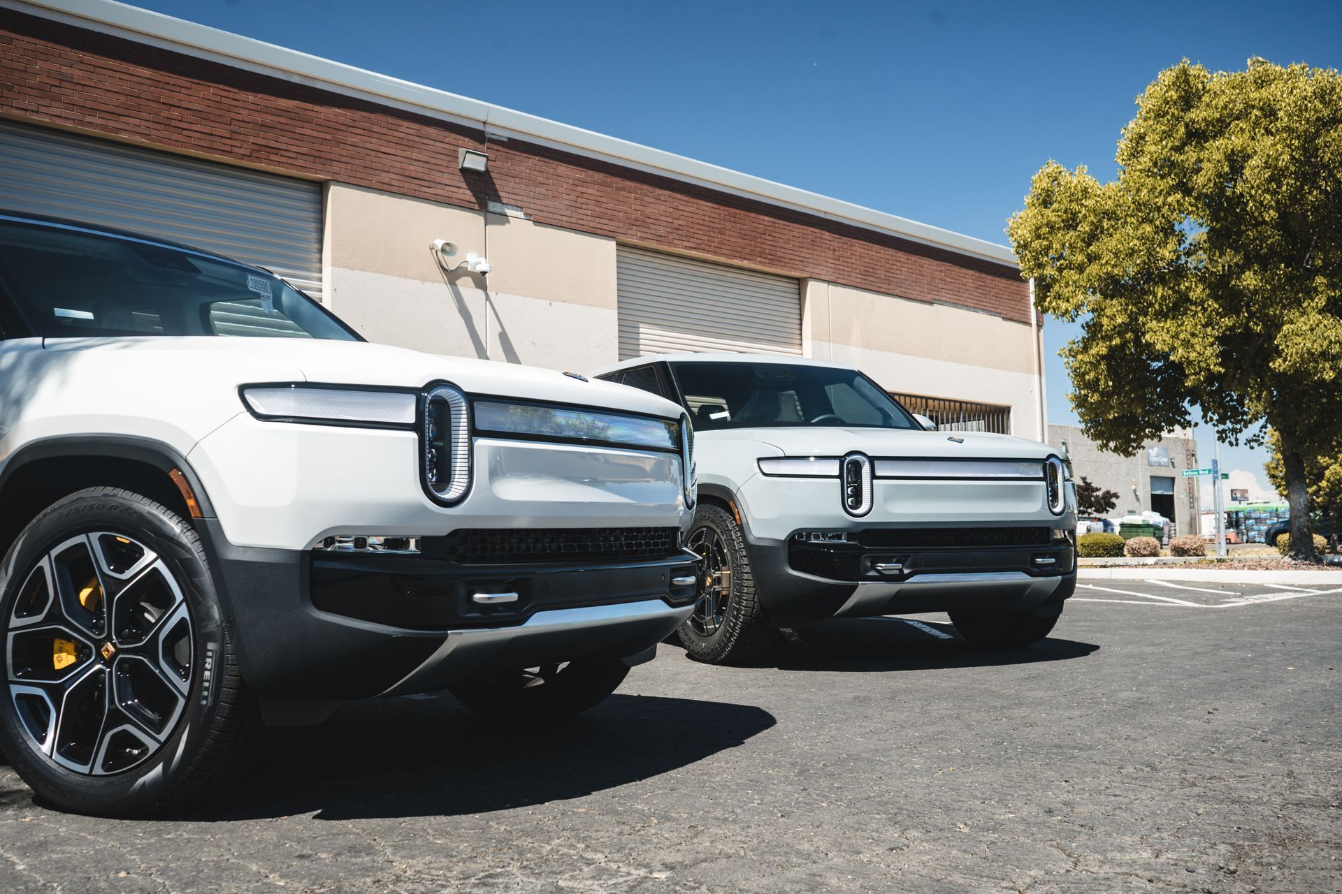 Two electric cars are parked next to each other in front of a building.