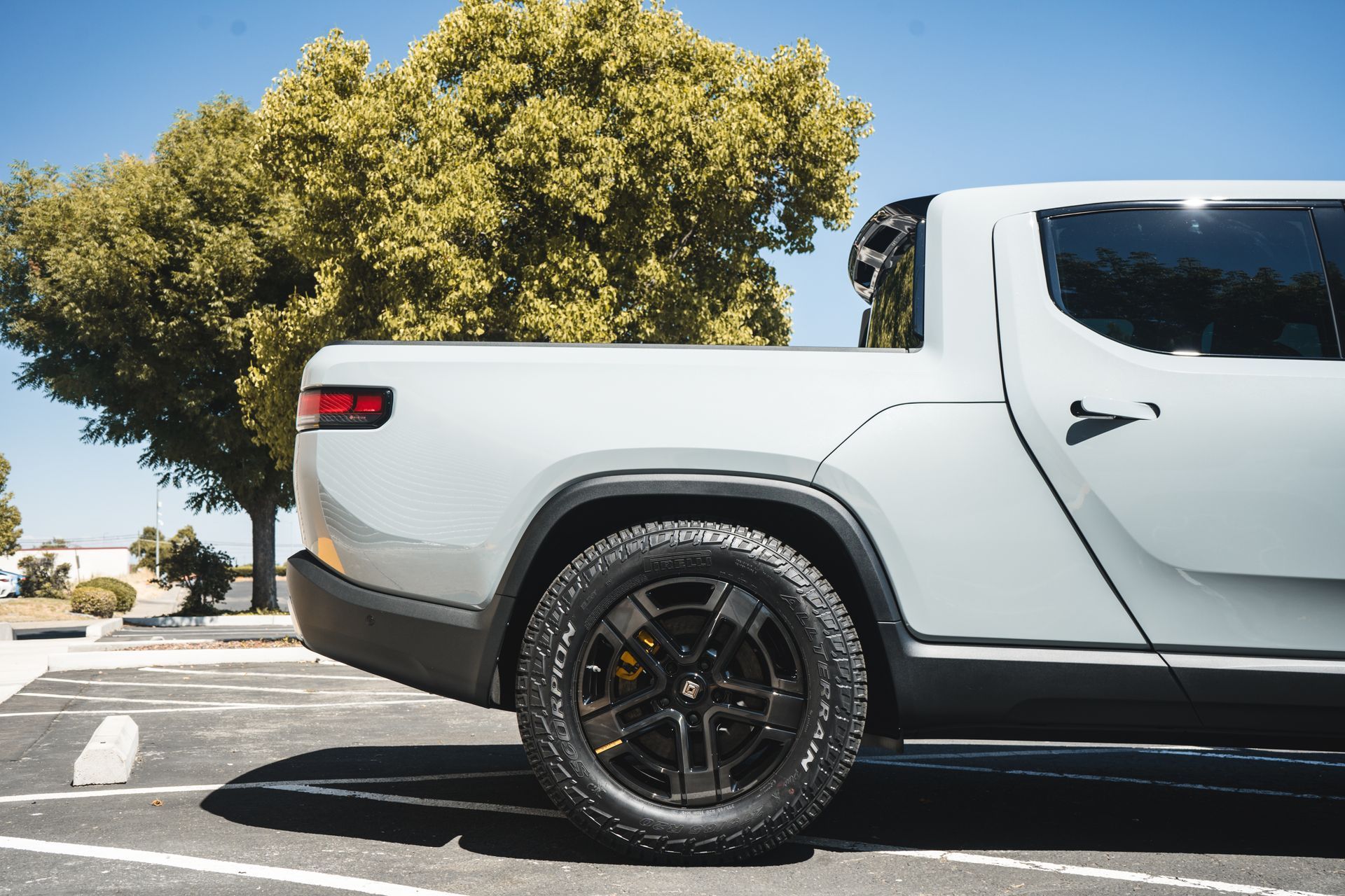 A white truck is parked in a parking lot with trees in the background.