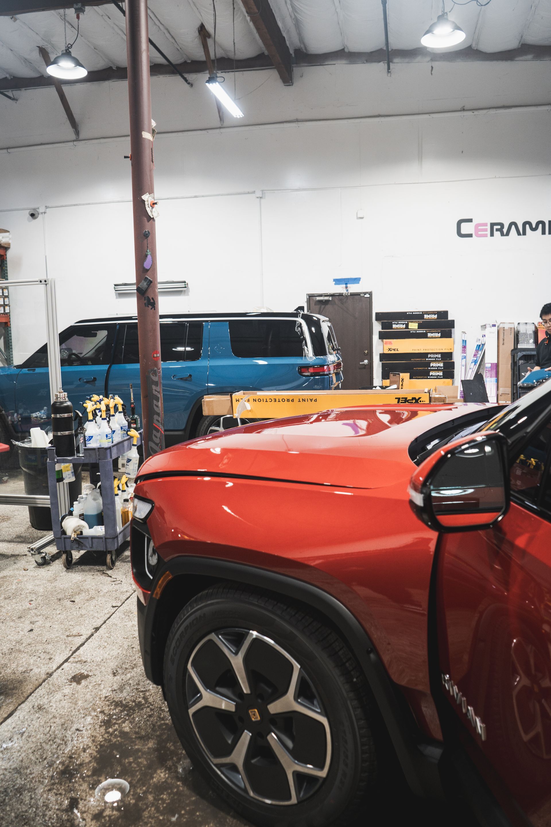 A red car is parked in a garage next to a blue car.