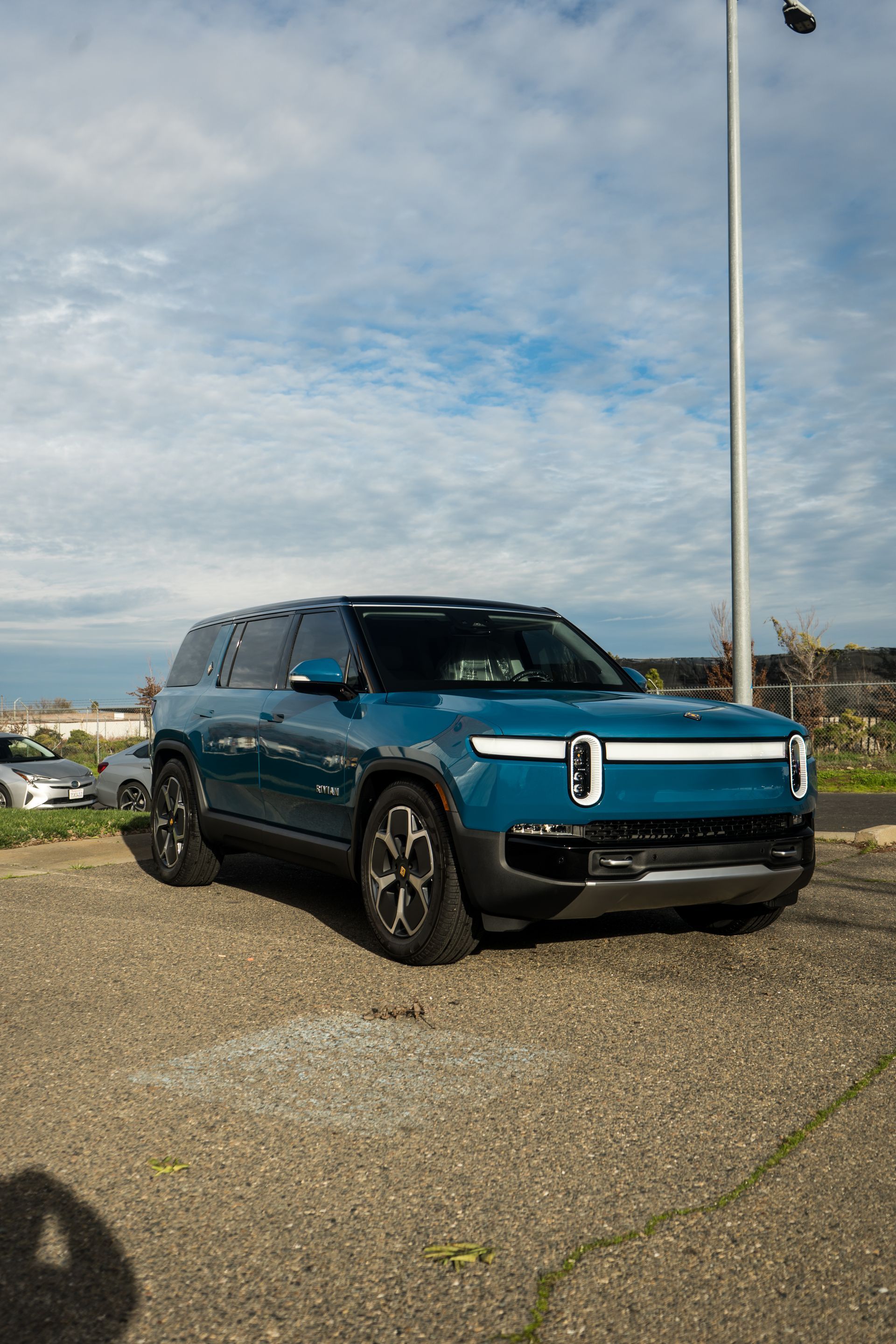 A blue suv is parked in a parking lot next to a street light.