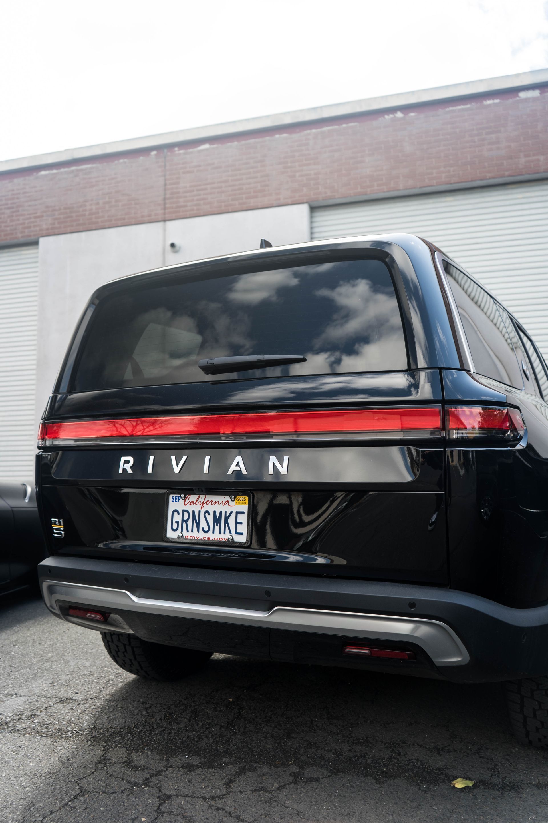 A black rivian suv is parked in front of a building