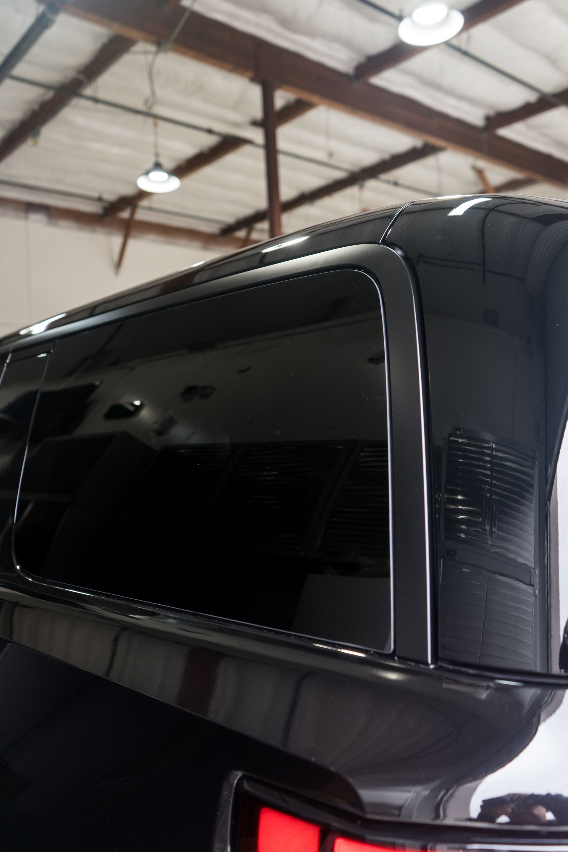 A black truck is parked in a garage with a large window