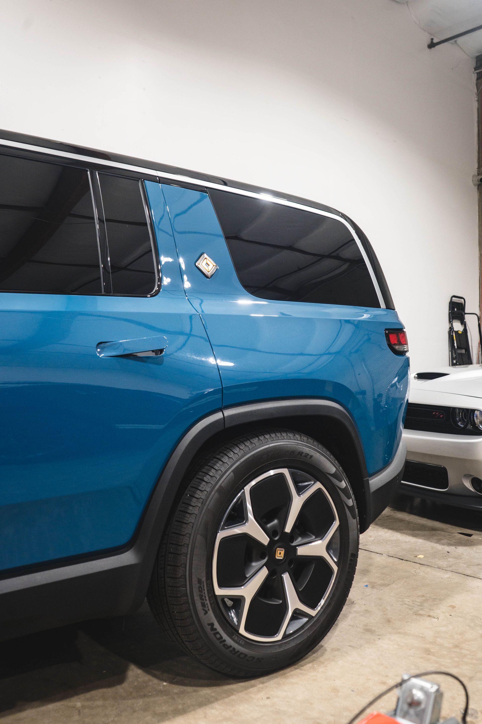 A blue suv is parked in a garage next to a white car.