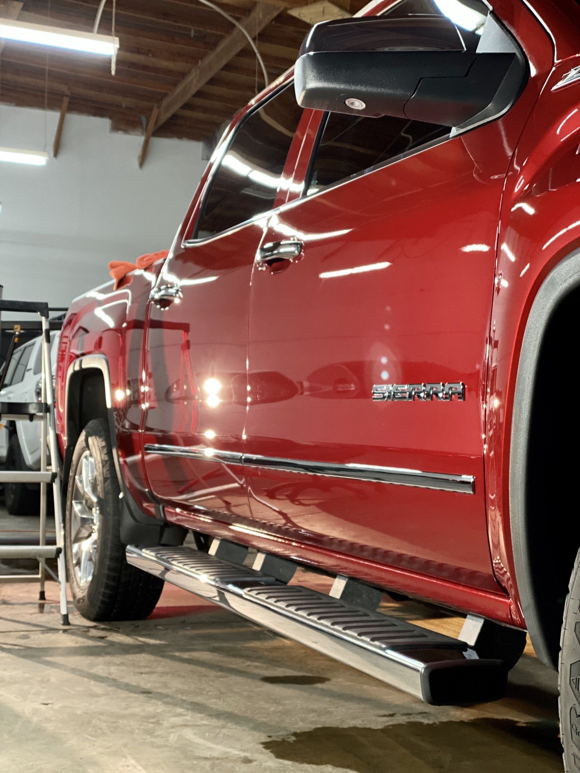 A red truck is parked in a garage next to a ladder.