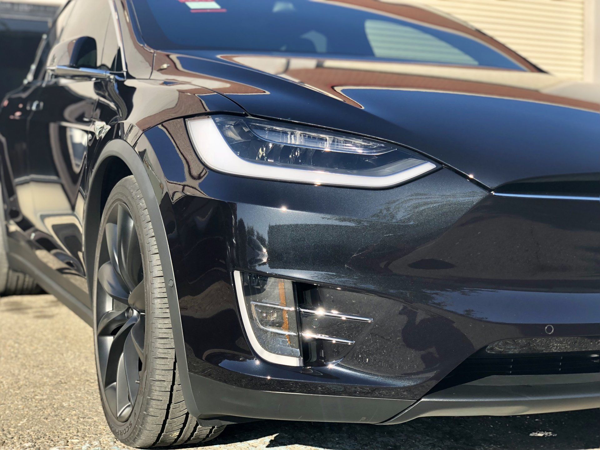 A black tesla model x is parked in a parking lot