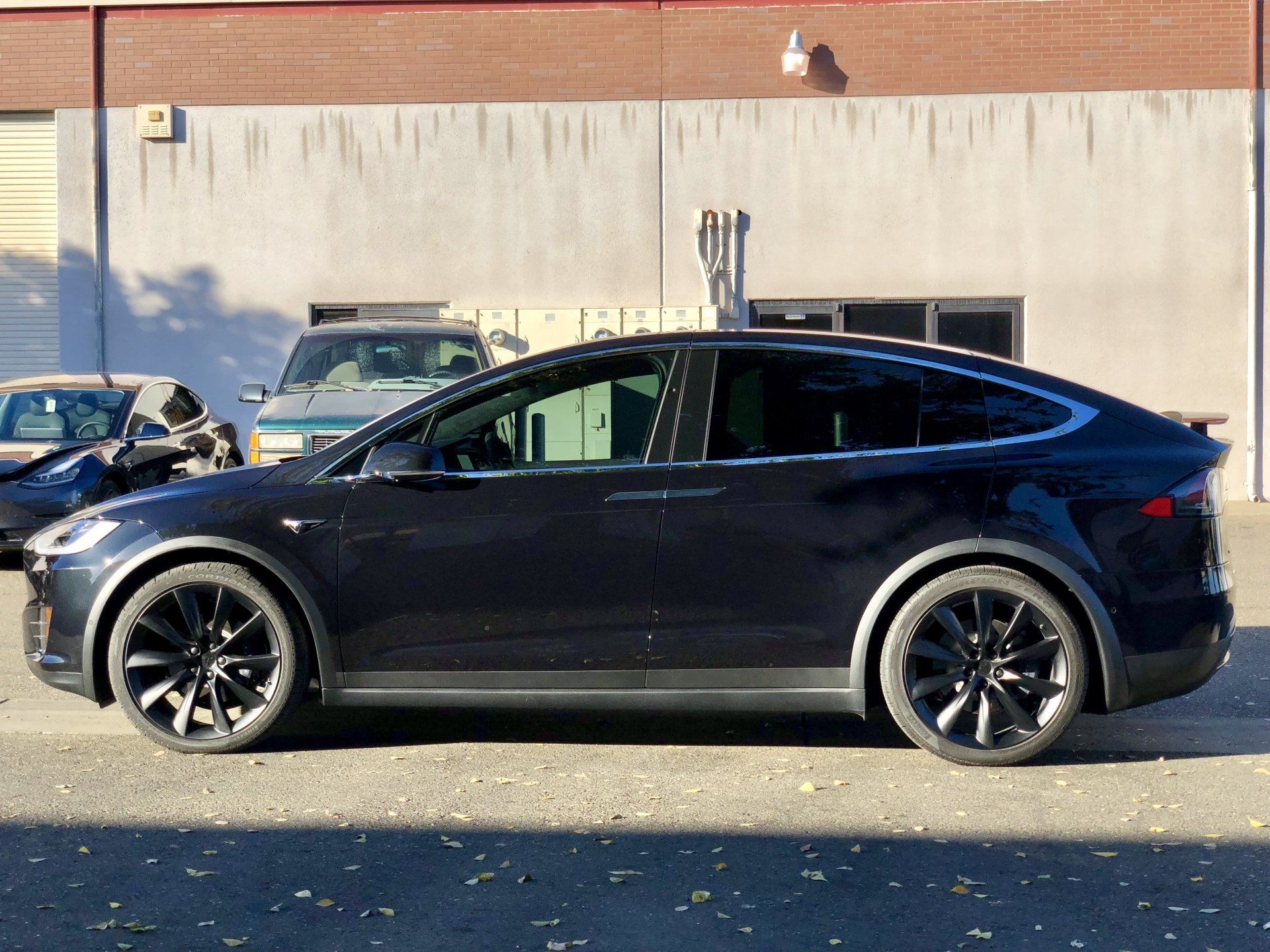 A black tesla model x is parked in front of a building.