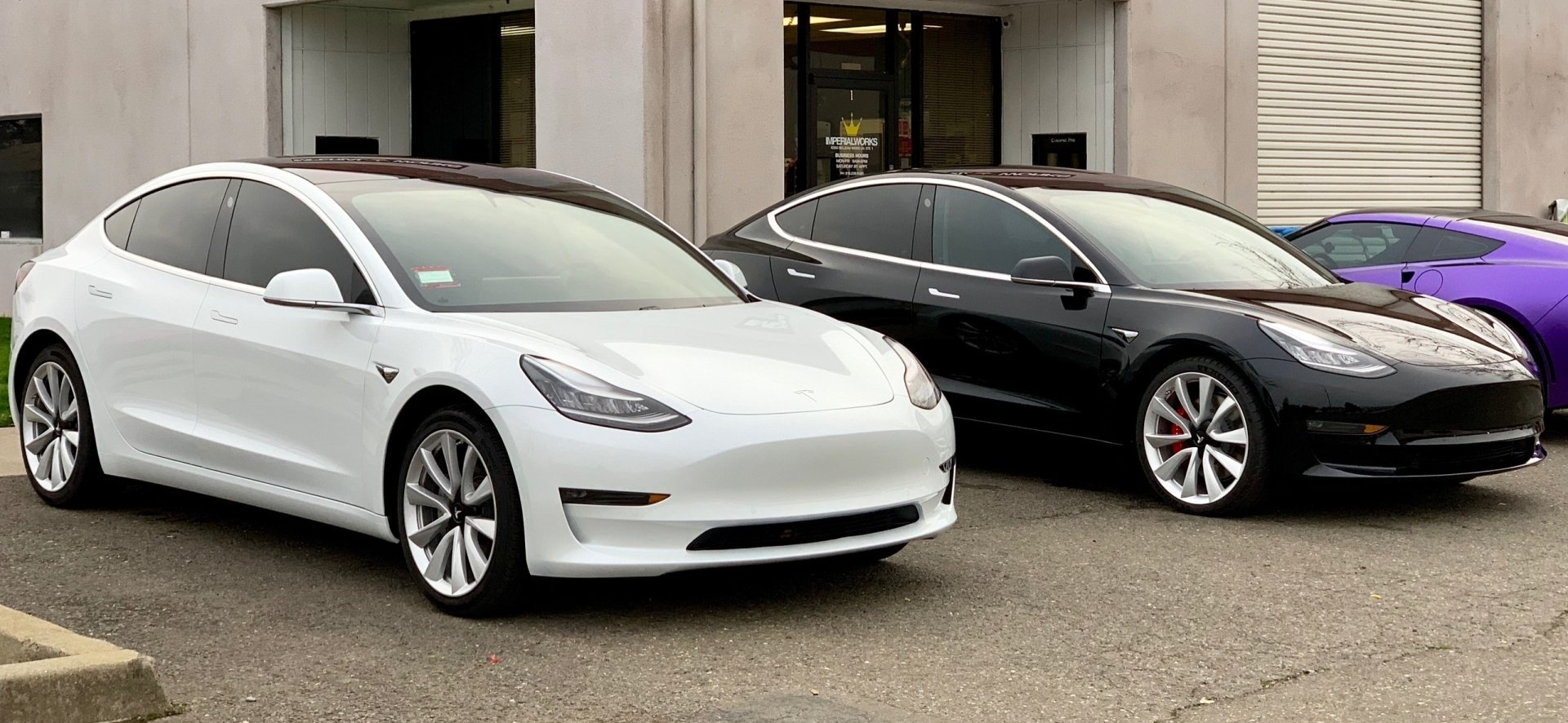 Two tesla model 3 cars are parked next to each other in a parking lot.