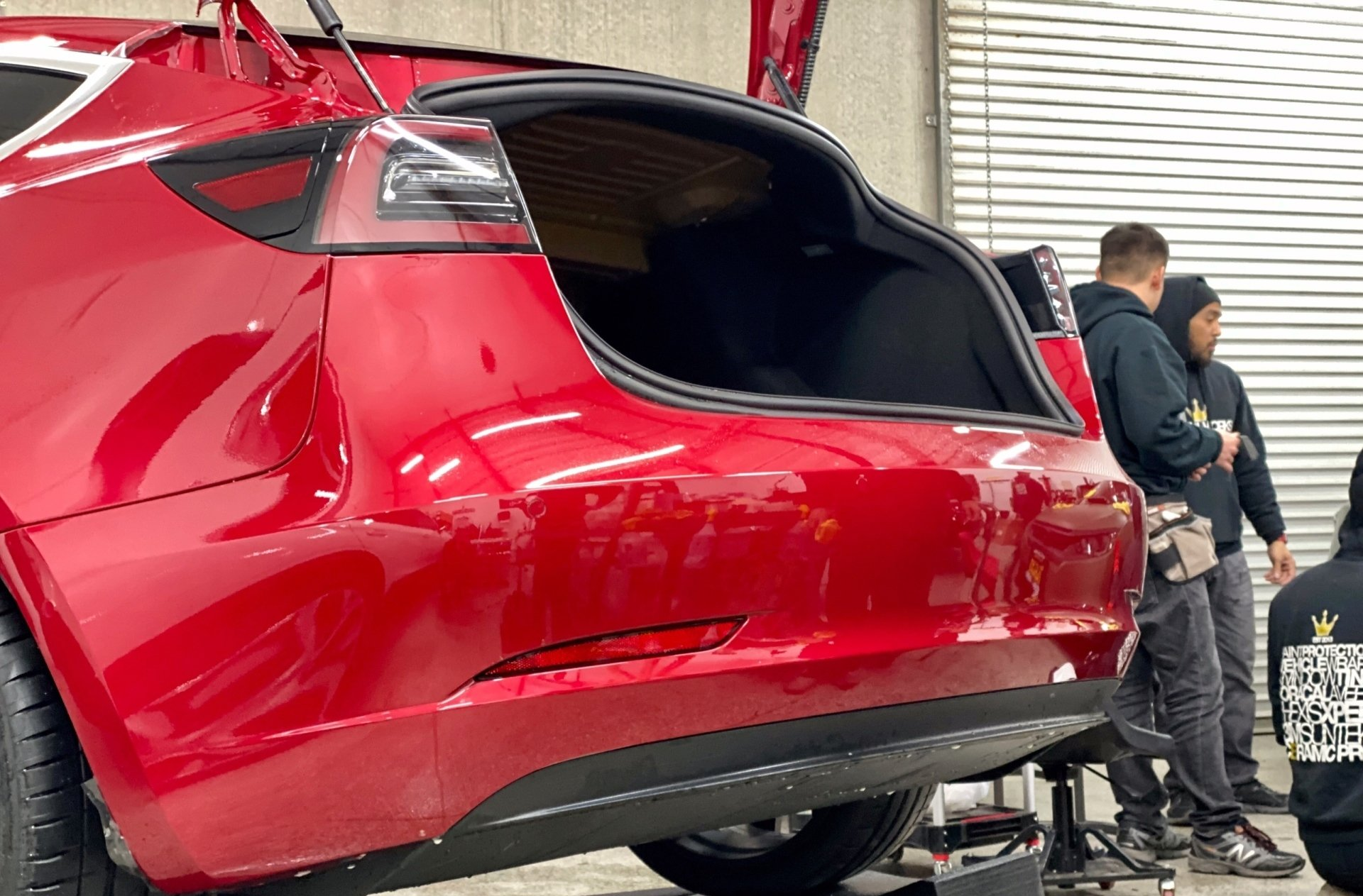 A group of men are working on a red tesla model 3.