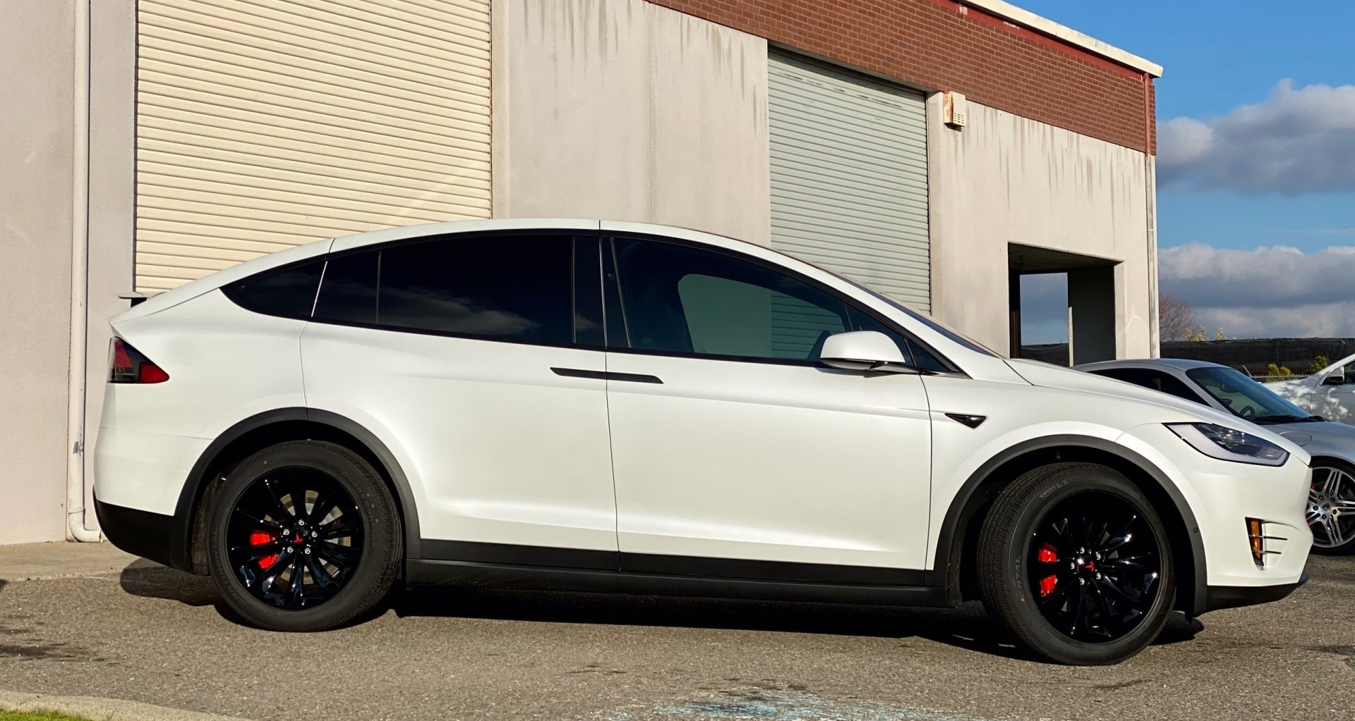 A white tesla model x is parked in front of a building.