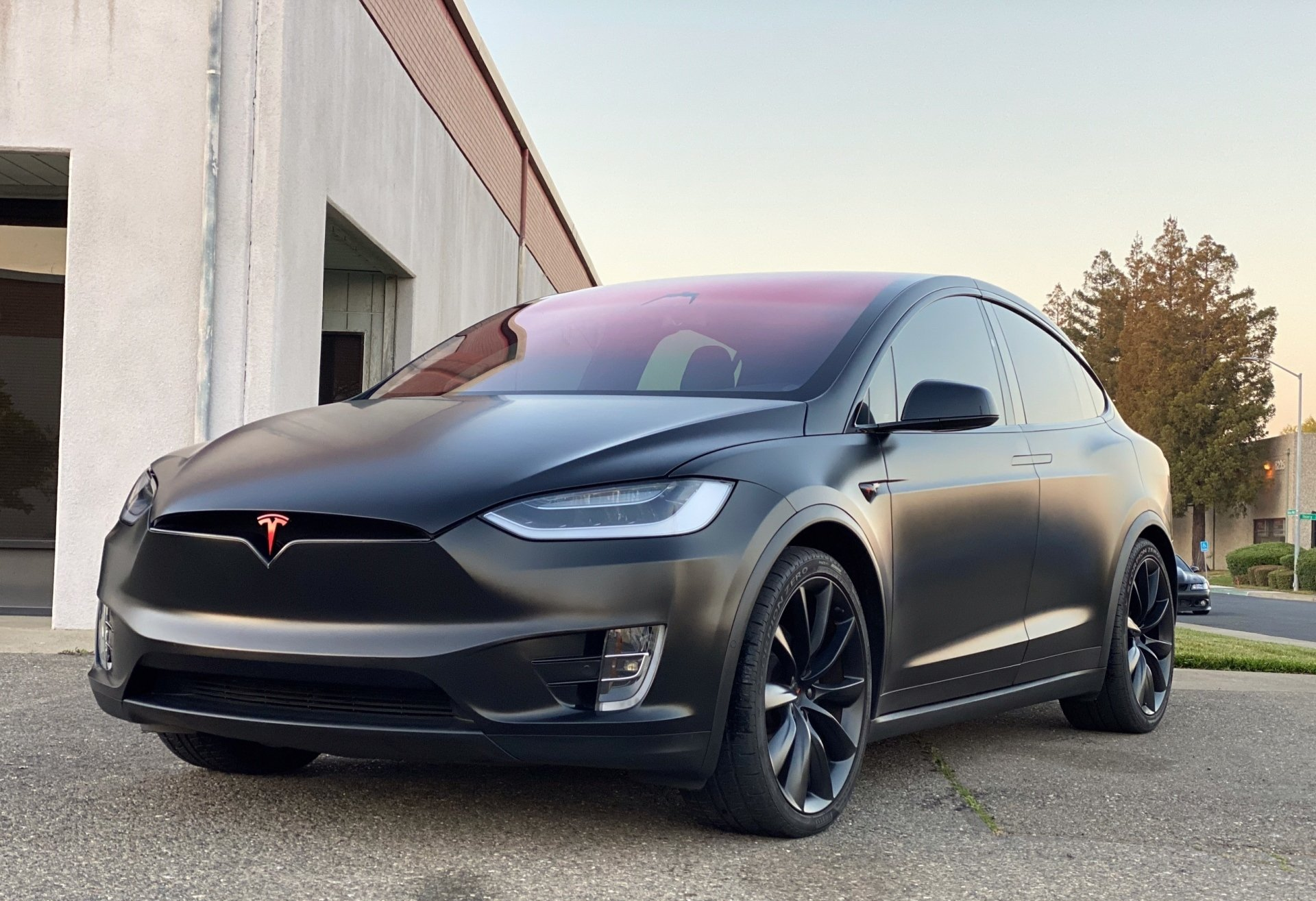 A black tesla model x is parked in front of a building.