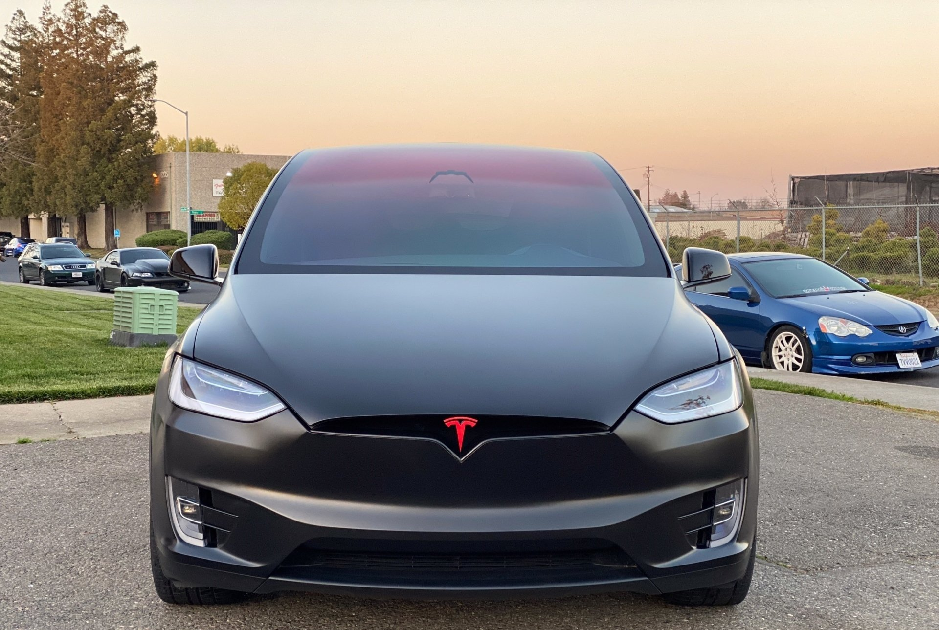 A black tesla model x is parked in a parking lot