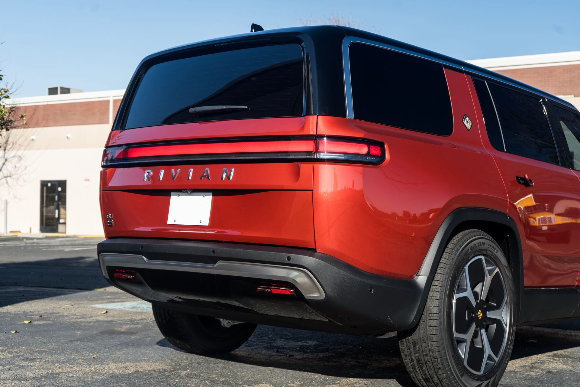 A red suv is parked in a parking lot in front of a building.