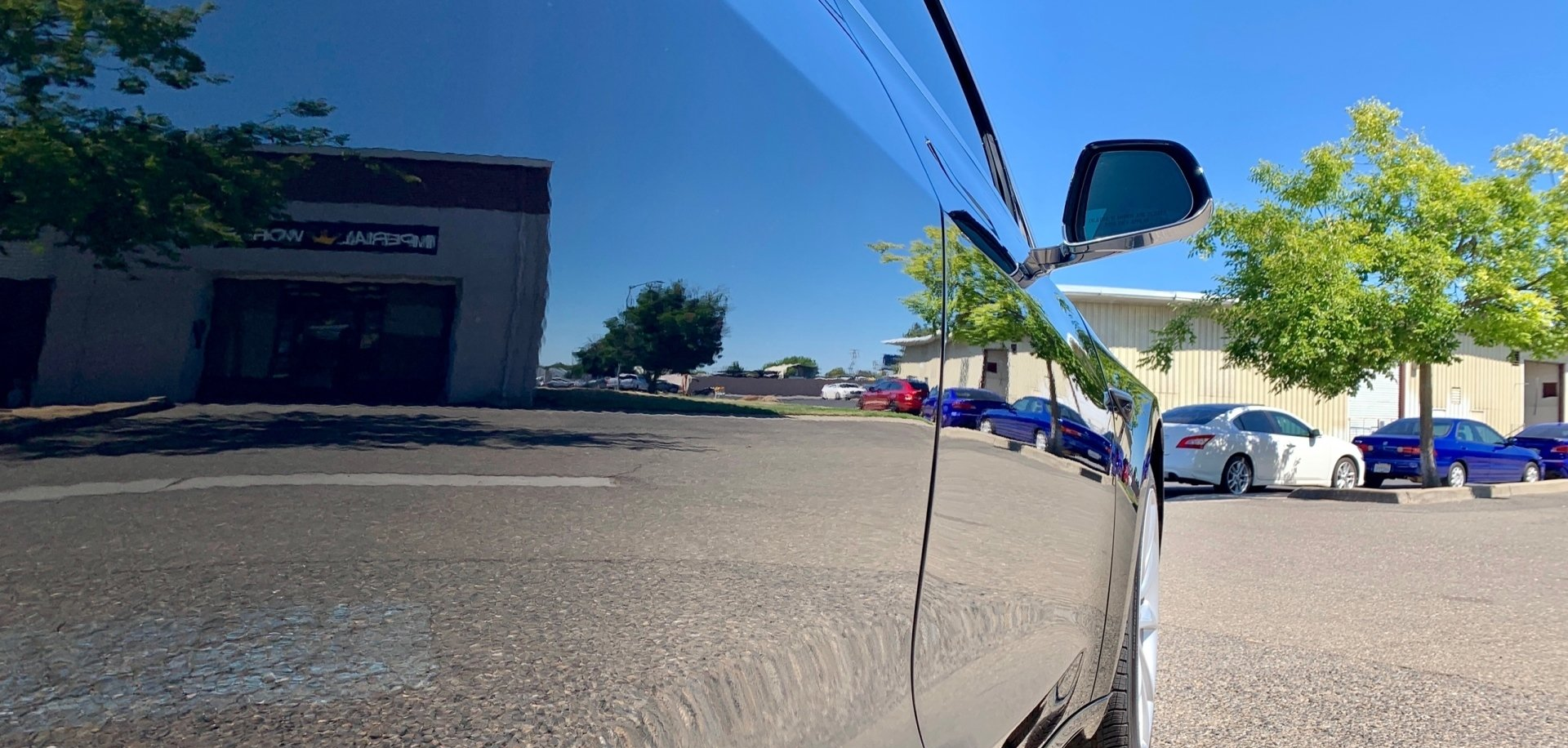 A car is parked in a parking lot in front of a building.