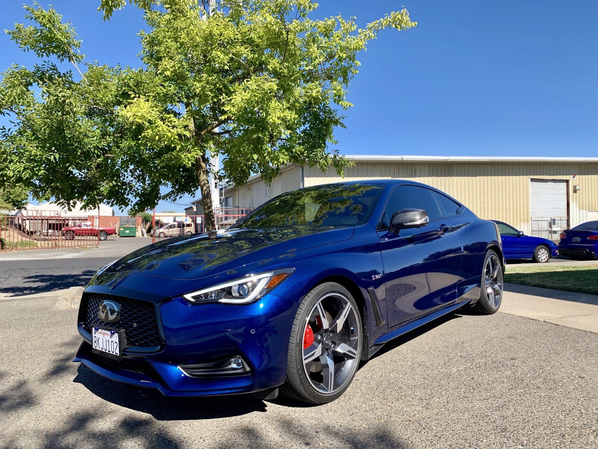 A blue infiniti q50 coupe is parked in front of a building.