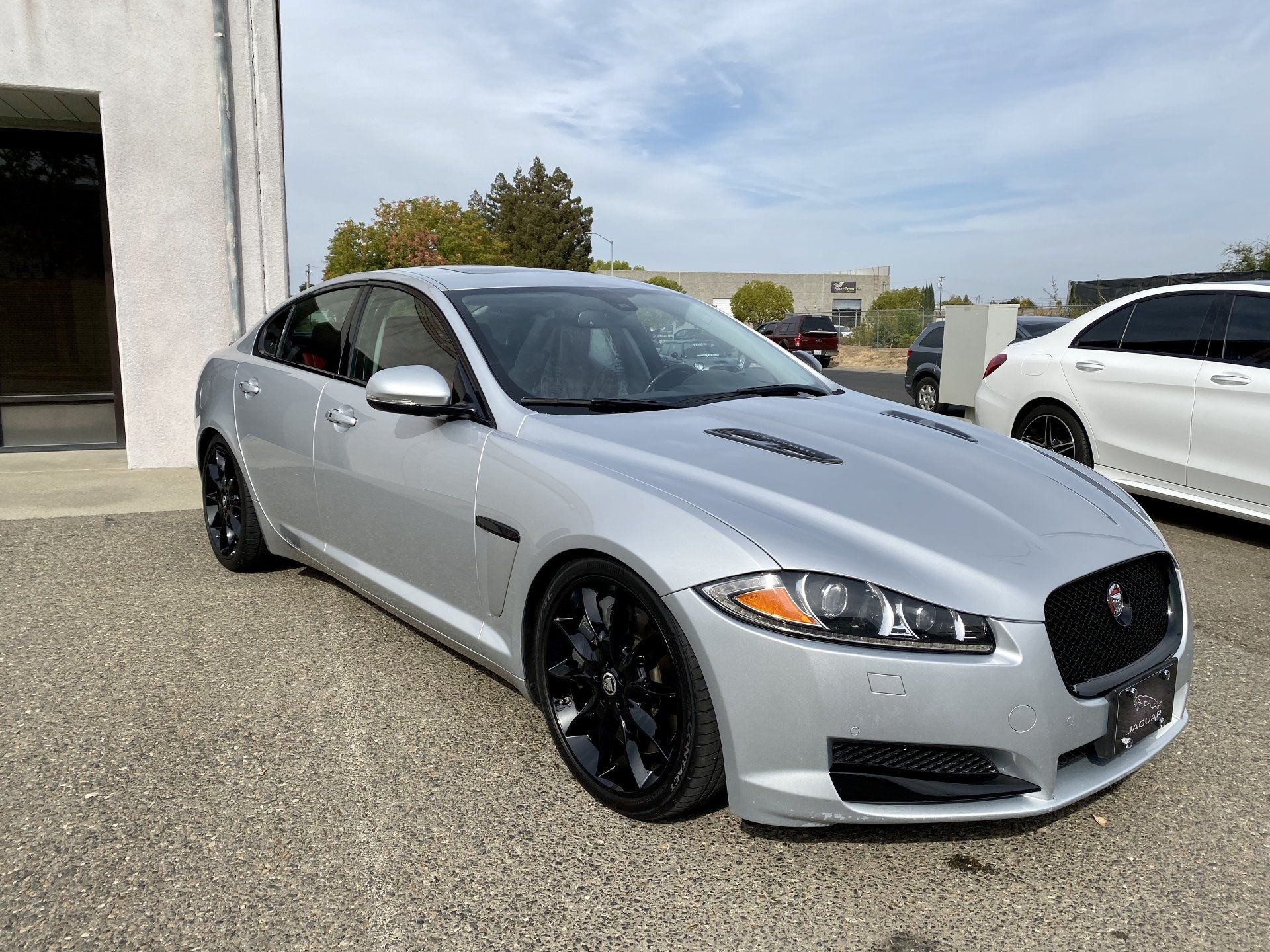A silver jaguar f type is parked in front of a building.