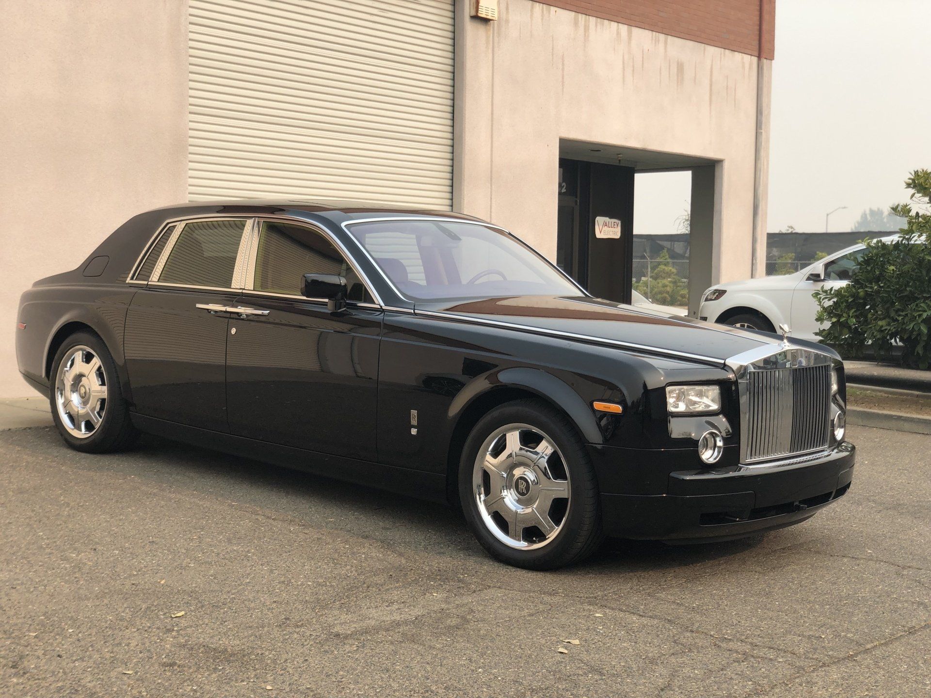A black rolls royce parked in front of a building.