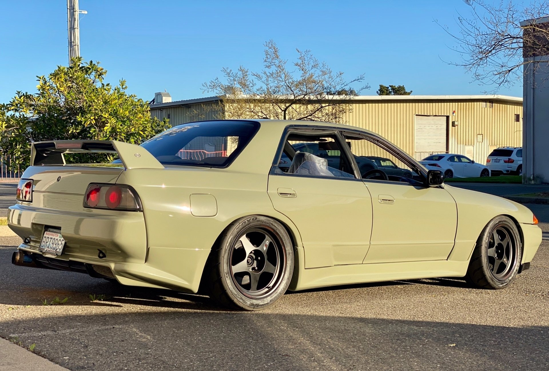 A green car is parked on the side of the road in front of a building.