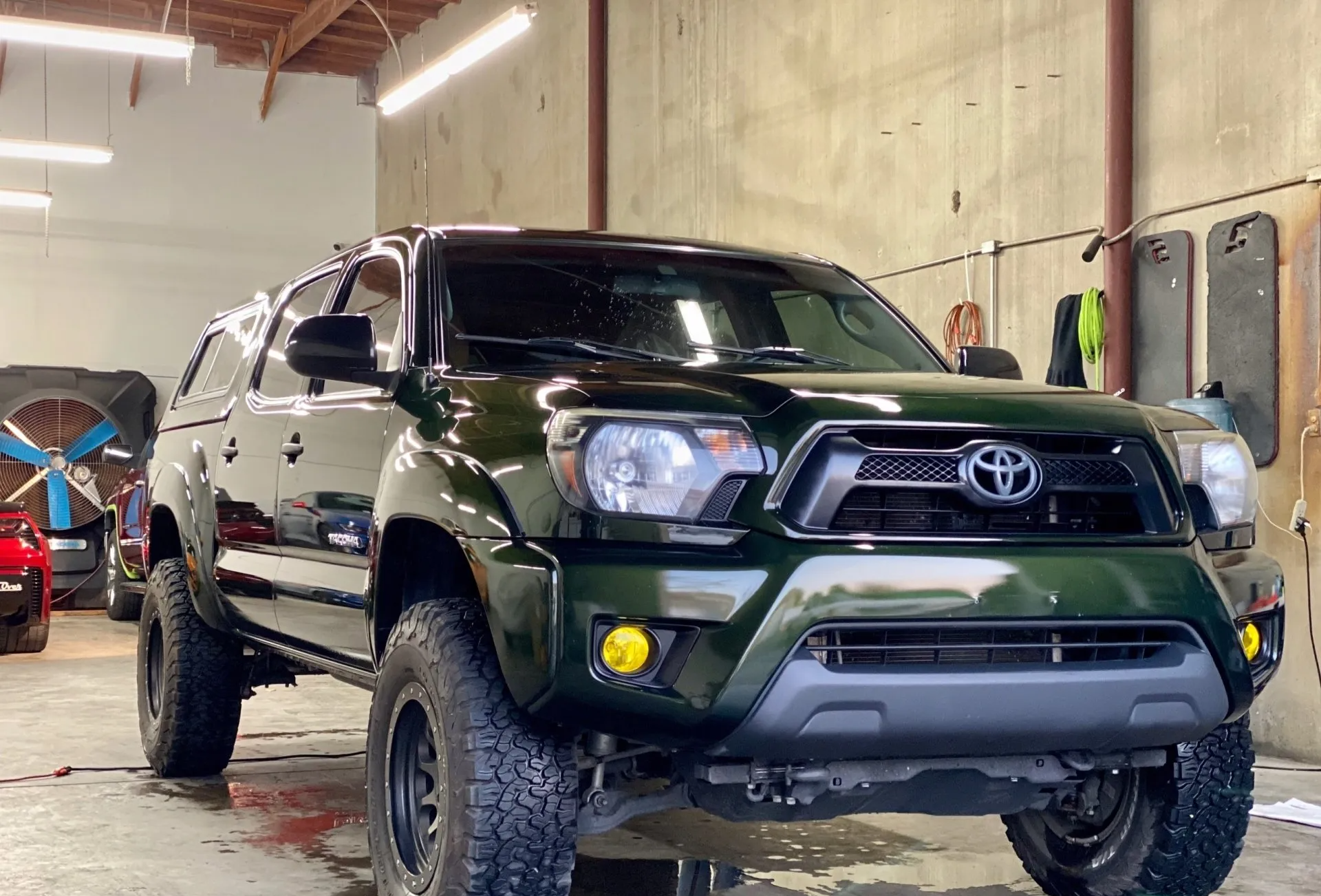 A green toyota tacoma is parked in a garage.