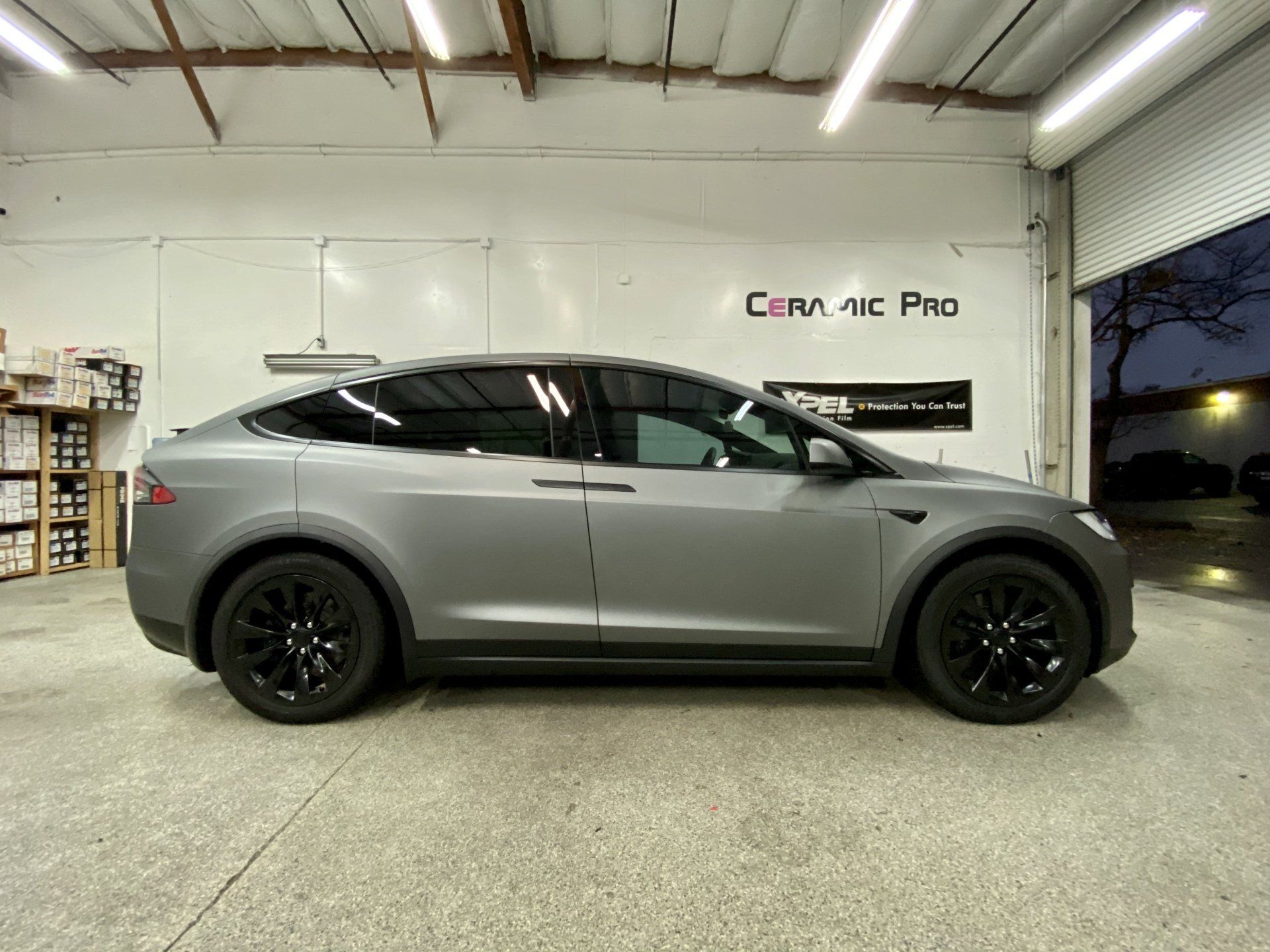 A gray tesla model x is parked in a garage.