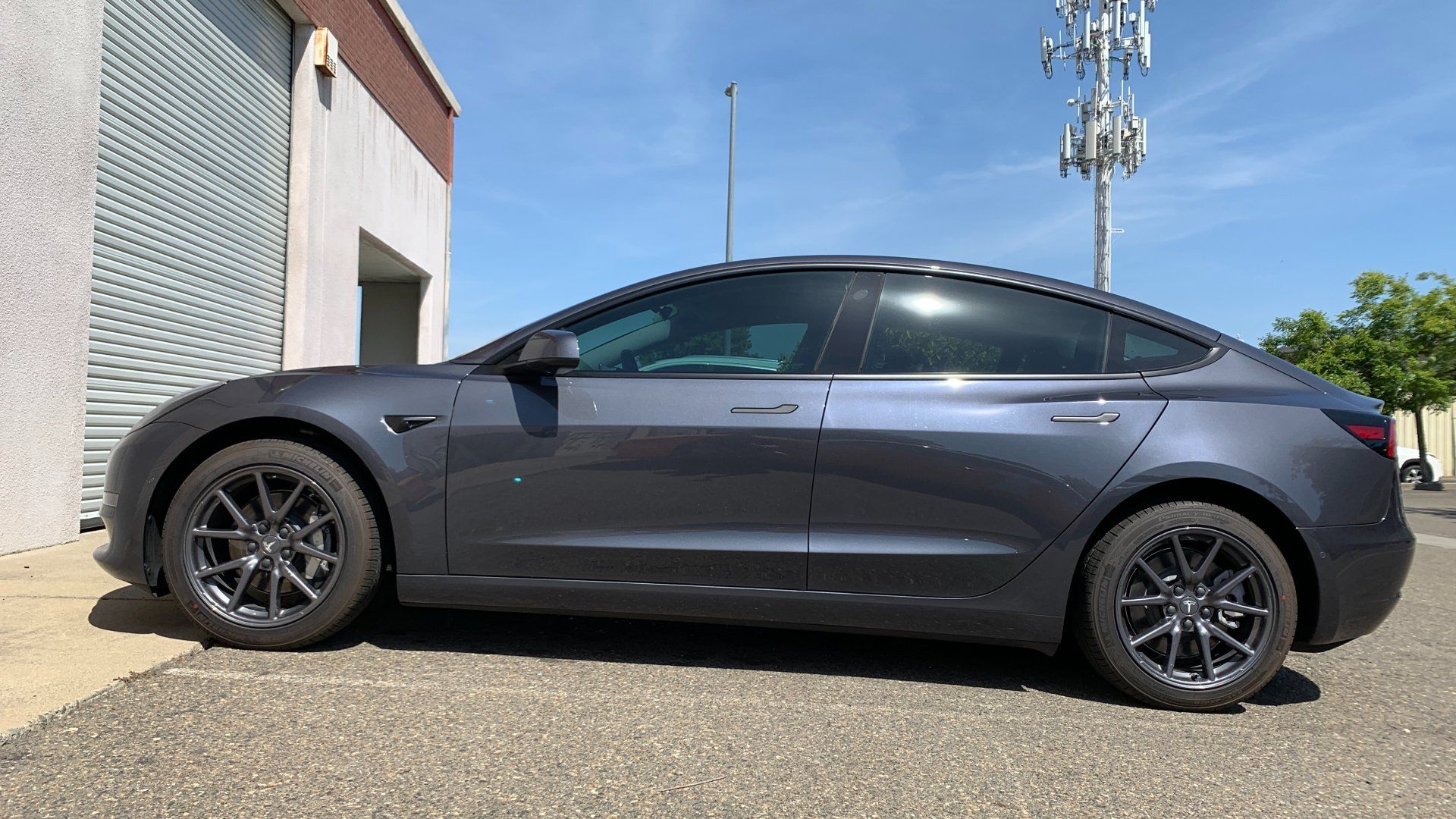 A tesla model 3 is parked in front of a building.