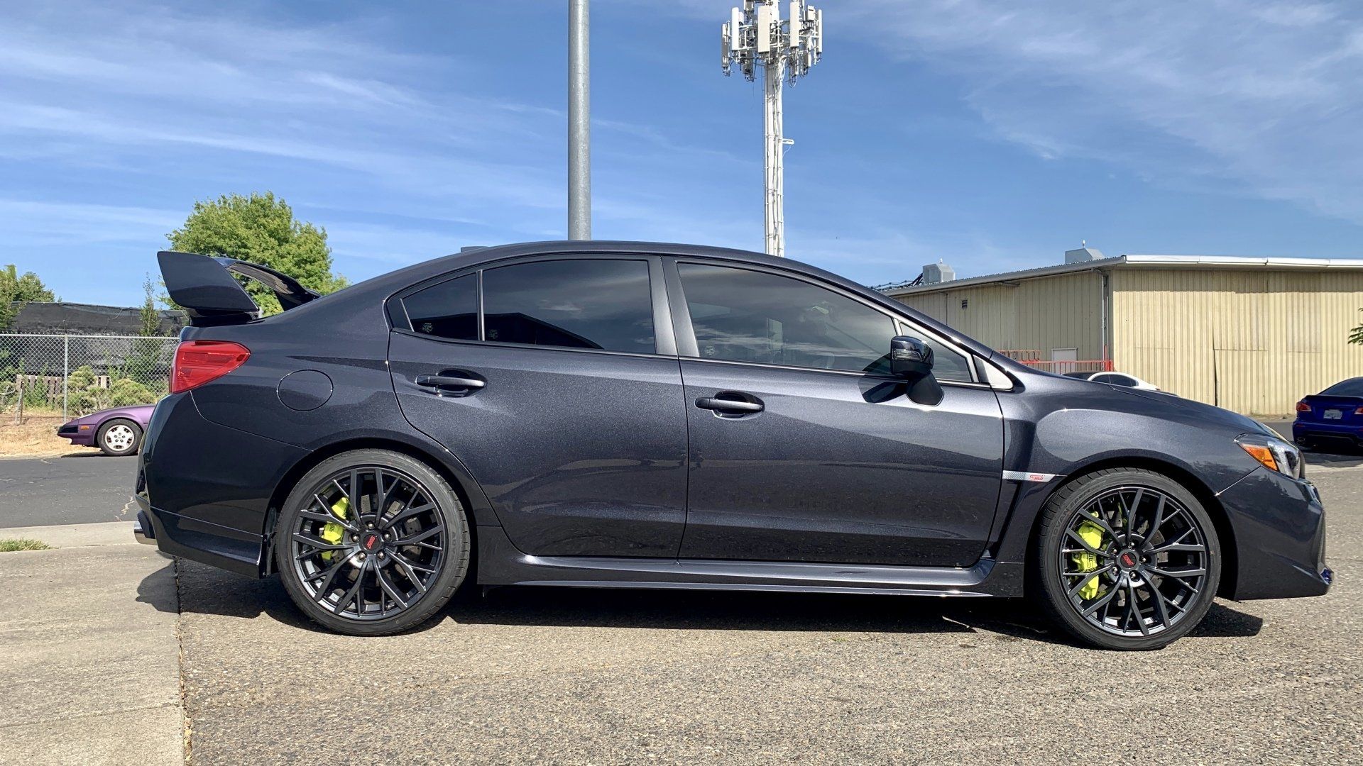 A black subaru wrx sti is parked in a parking lot.