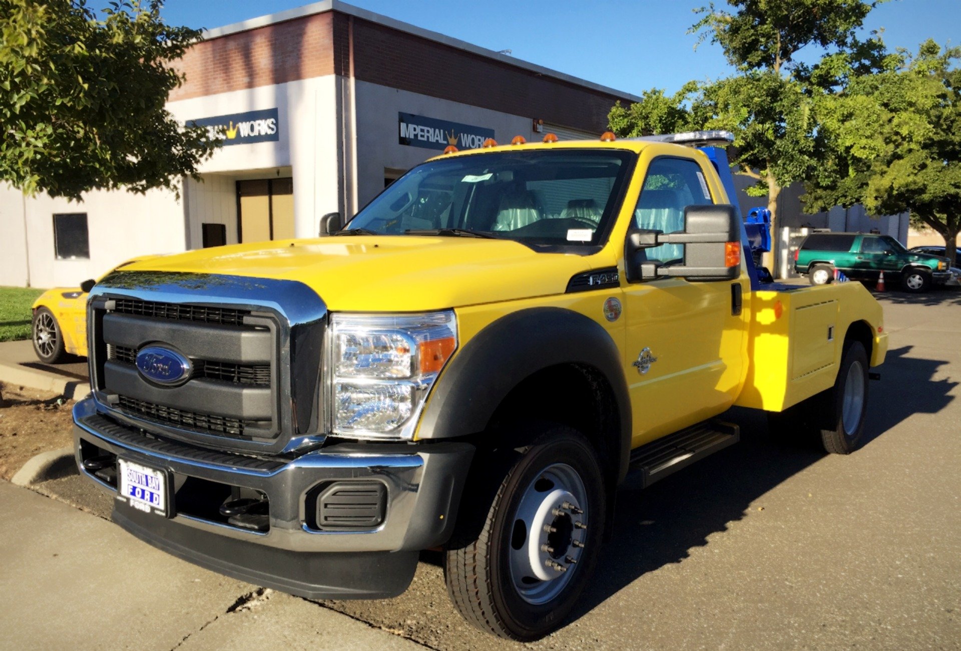 A yellow tow truck is parked in front of a building