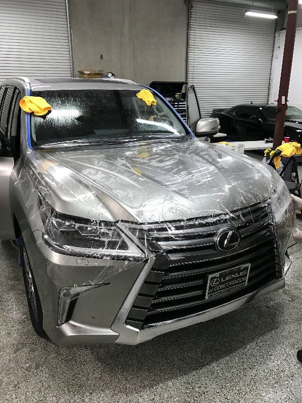 A silver lexus lx 570 is wrapped in plastic in a garage.
