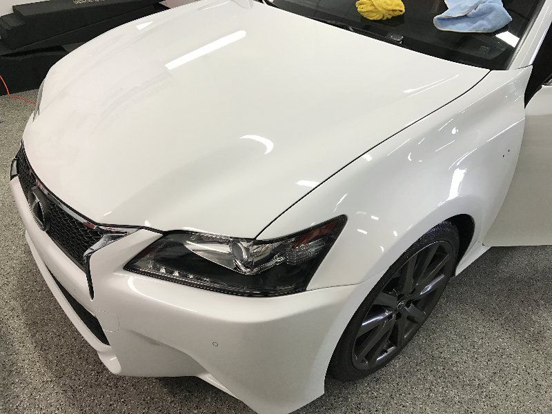 A white car is parked in a garage with the door open.