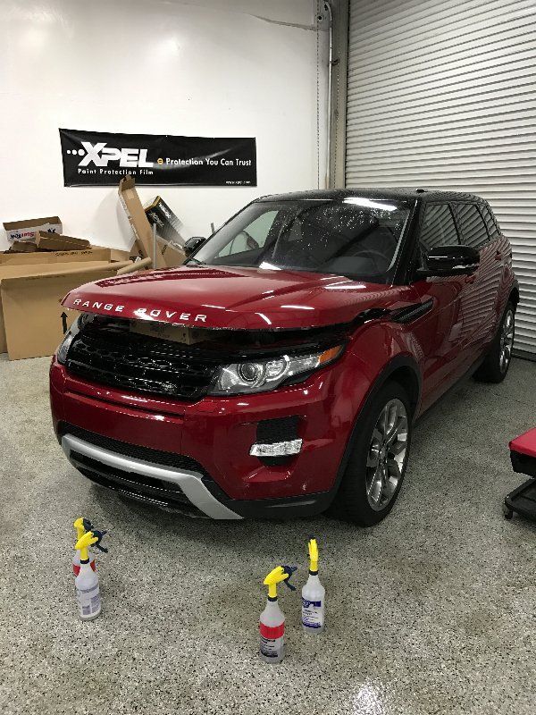 A red range rover evoque is sitting in a garage next to spray bottles.