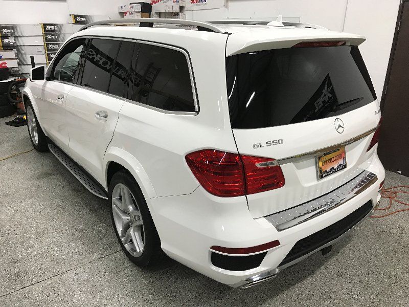 A white mercedes benz gl550 is parked in a garage.